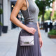 Woman holding a silver handbag on a city street