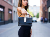 Woman holding a black handbag on a city street